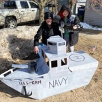 Camryn Reynolds stands next to their USS_Cam battleship sled.