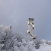 Azure's fire tower sits covered in snow in front of a cloudy sky.