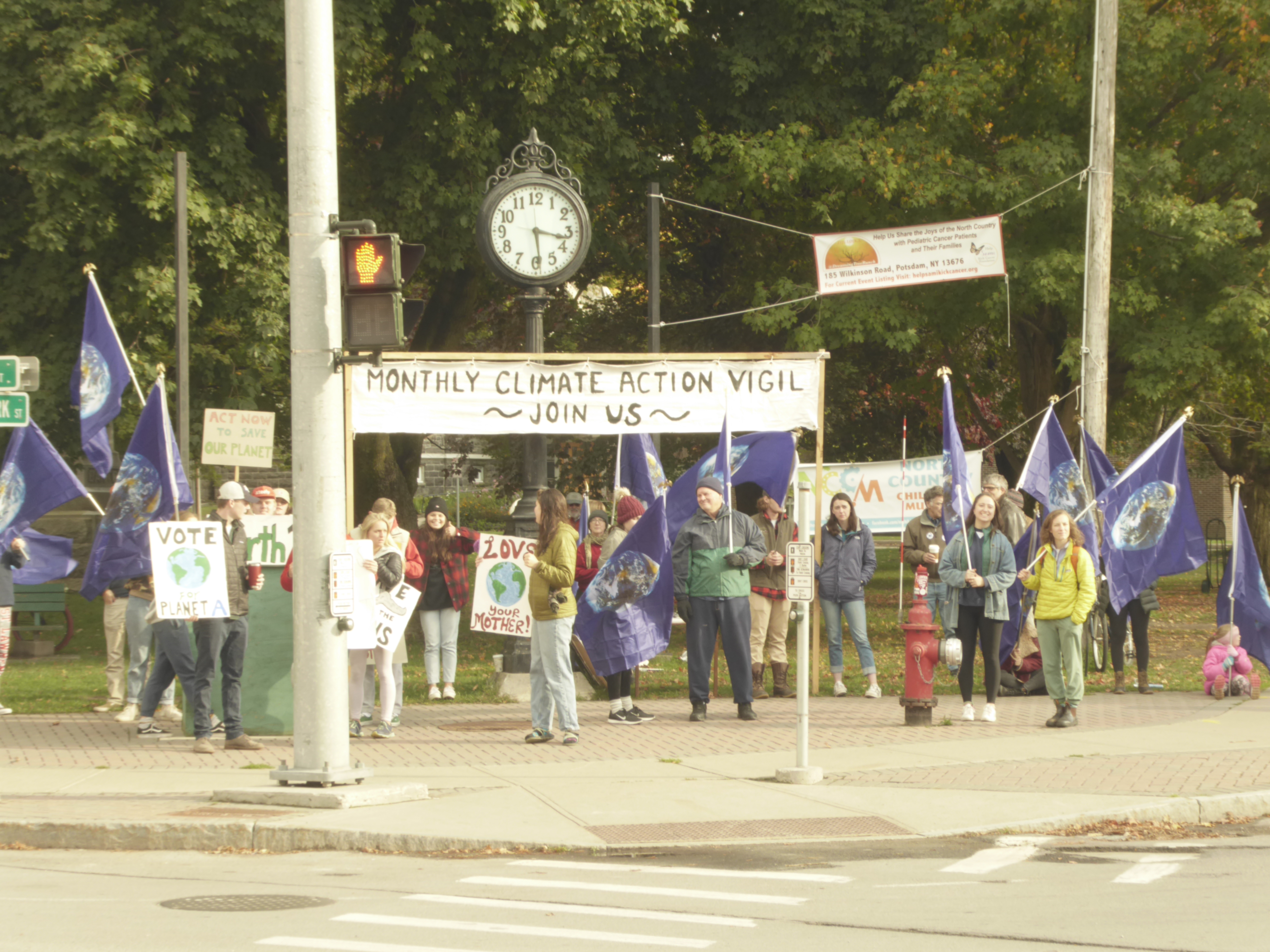 Protesters hold signs and flags at the climate vigil in Canton.
