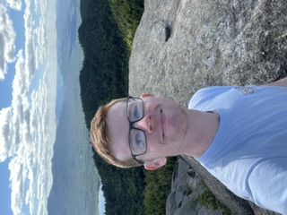 AJ at the summit of a mountain