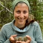 Women with brown hair and green bandana holding three brown baby critters