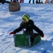 One member of the team the I-Don't-Knows races down the hill in his cardboard sled