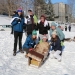 The 7 member sled team Calc-U-SUS from Clarkson gathers for a group photo with the remains of their speedy cardboard sled