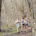 A group of three women running down a wooded trail