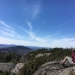 A hiker sits to the right on rocks on Ampersand Mountain in New York State's Adirondacks.